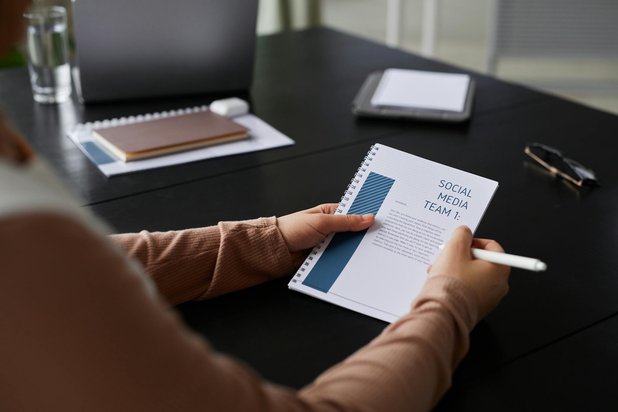 About 1 Close-up of a businesswoman holding a social media team notebook in a professional setting.