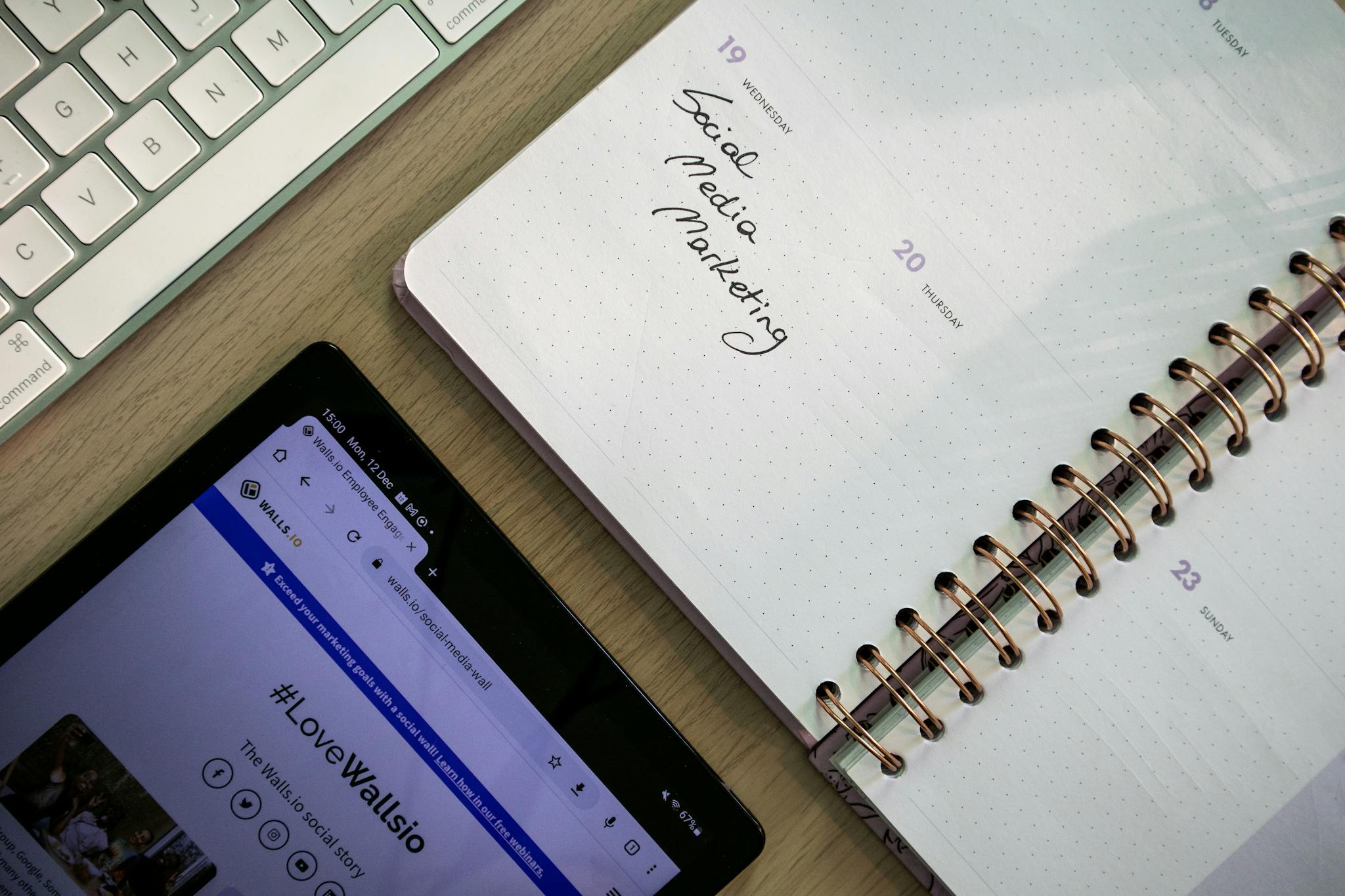Contact 1 Top view of a notebook, tablet, and keyboard used for social media marketing planning.